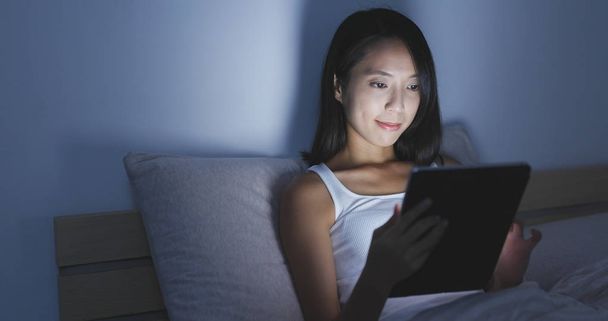Жінка працює на планшетному комп'ютері на ліжку
  - Фото, зображення