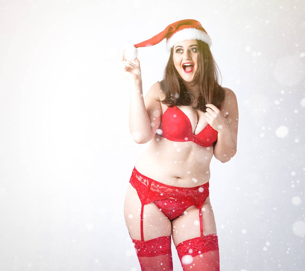 Gelukkig schattig dik Santa meisje. Model in rode lingerie en KERSTMUTS.  - Foto, afbeelding
