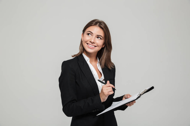 Portrait of a smiling young businesswoman in suit - Foto, afbeelding