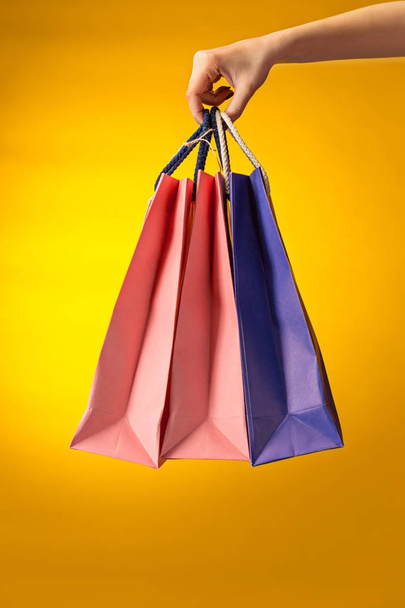 Female hand holding bright shopping bags - Foto, imagen