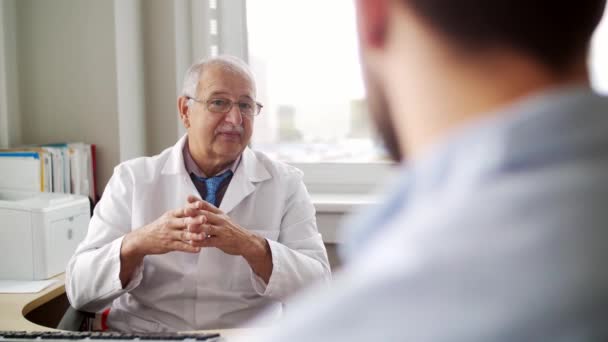 starszy lekarz mówi do pacjenta w szpitalu - Materiał filmowy, wideo