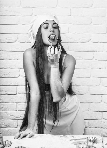 Pretty girl licks cookie cutter - Foto, afbeelding
