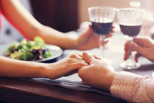 ワインを飲むと、手を繋いでいるグルメ レストランでロマンティックなディナーを食べるカップル - 写真・画像