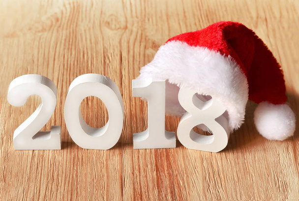 santa cap on rustic wooden background with figures 2018 - Photo, image