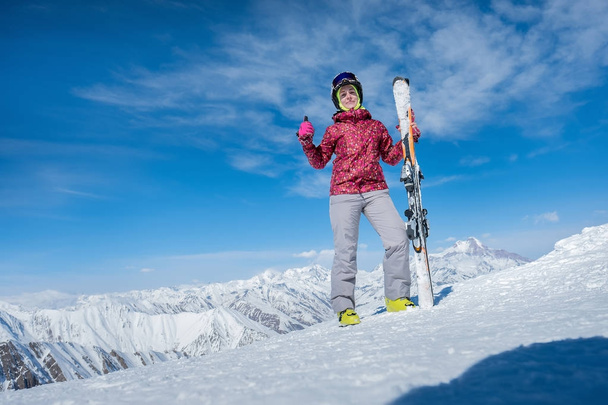 girl is standing on the slope with alpine skiing. Shows a thumb. - Photo, Image