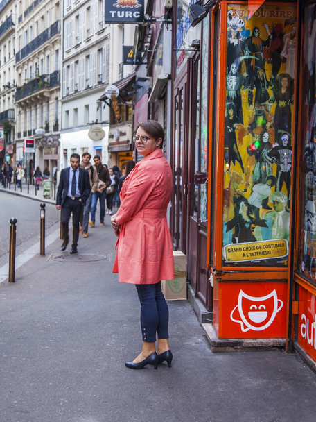 パリ、フランス、2017 年 10 月 27 日に。人々 は、秋の朝の通りに沿って行きます。明るいレインコートで若い魅力的な女性が振り返る - 写真・画像