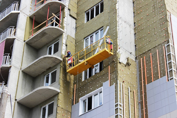 çalışan sarı açık asma beşikteki bir yeni inşa edilen yüksek katlı bina - Fotoğraf, Görsel
