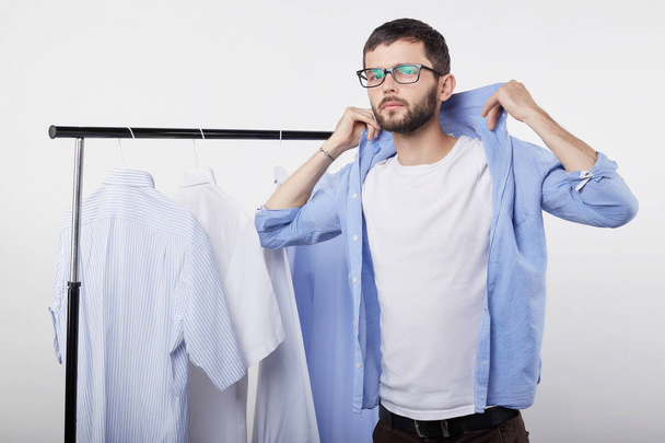 Portrait of stylish confident young male video blogger fitting new shirt in private dressing room for shooting tutorial for his traveling vlog. Fashionable European man trying new clothes in shop. - Photo, Image