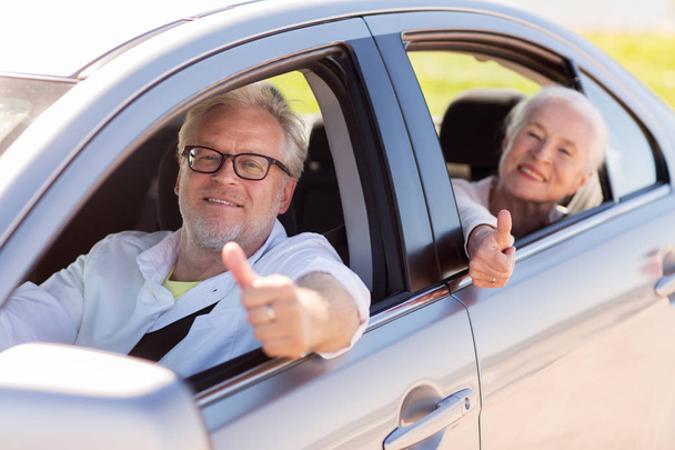 anziani coppia di guida in auto e mostrando pollici in su
 - Foto, immagini