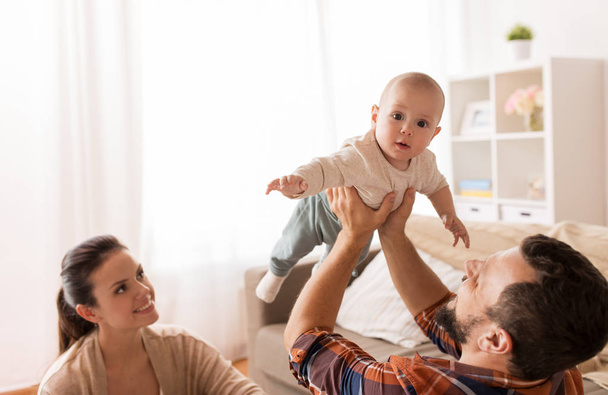 happy mother and father playing with baby at home - Fotó, kép
