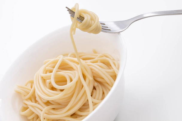 白いボール、フォーク、白い背景の上にプレーンの調理スパゲッティ パスタ. - 写真・画像