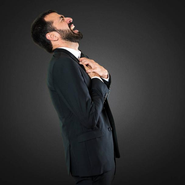 Handsome businessman with heart pain on black background - Foto, imagen