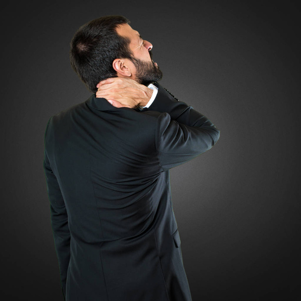 Handsome businessman with neck pain on black background - Photo, Image
