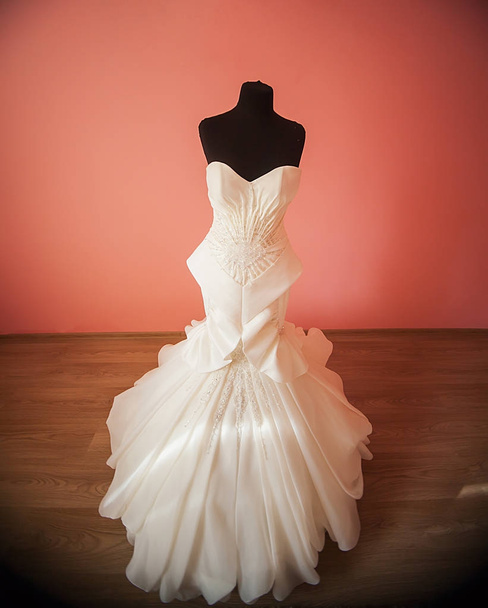 Svatební šaty visí na manekýně v místnosti nevěstu na její svatební den - Fotografie, Obrázek