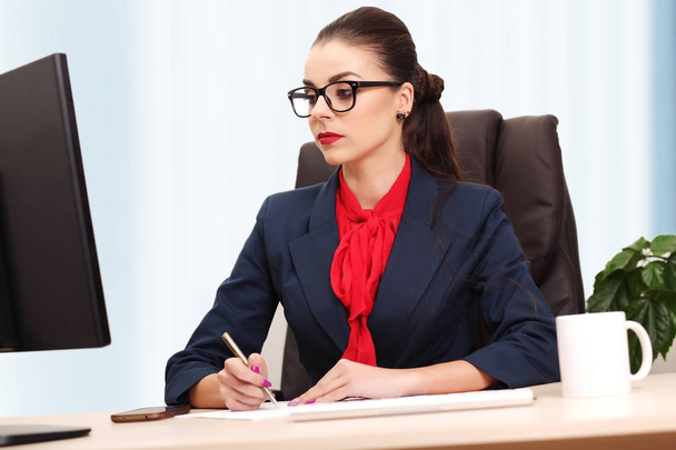 Portrait of businesswoman with laptop writes on a document at he - Photo, Image