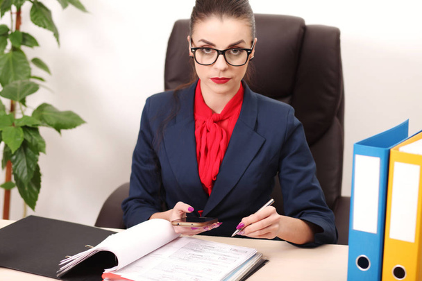Portrait of businesswoman with laptop writes on a document at he - Photo, Image