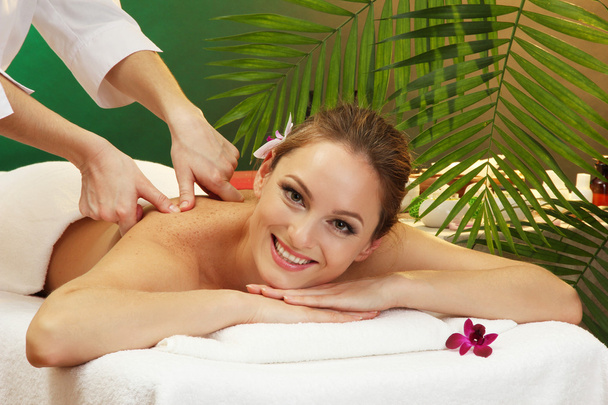 bela mulher no salão de spa com pedras recebendo massagem, no fundo verde
 - Foto, Imagem
