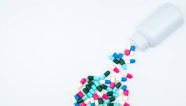 Antibiotic capsules spilling out of pill bottle on white background with copy space, just add your own text. Antibiotic drug use with reasonable concept. - Photo, Image