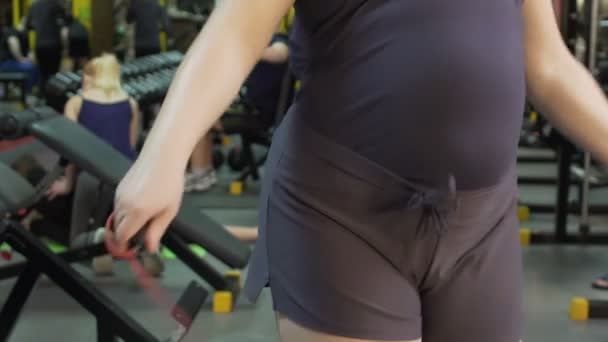 Sweating overweight girl skipping jump rope in sports club, fitness, slow-mo - Záběry, video