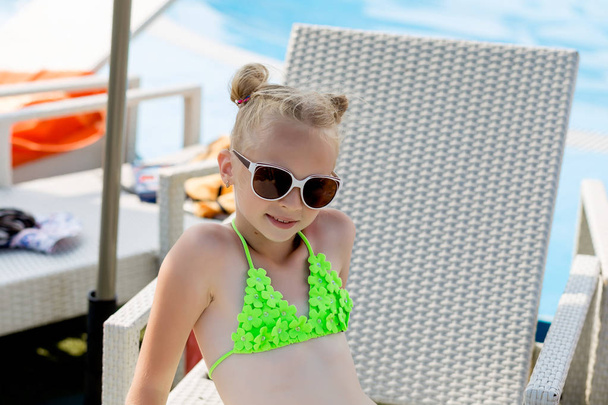 junges Mädchen im Badeanzug auf einem Regal am Pool - Foto, Bild