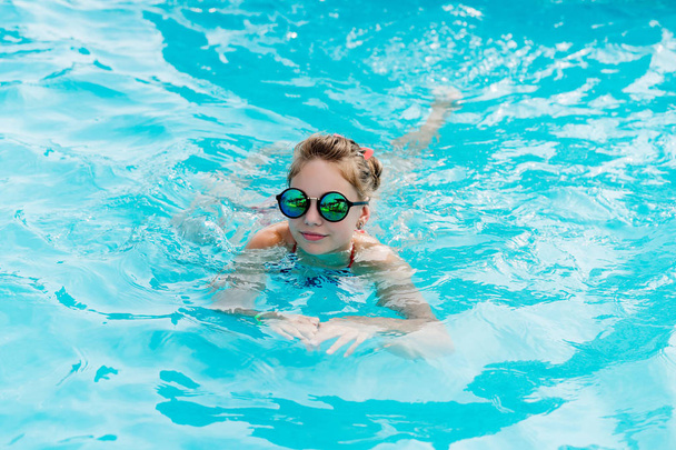 Beautiful girl in a swimsuit swims in the pool - Фото, зображення