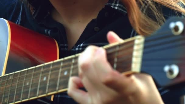 female hands play the guitar. A happy carefree young girl plays the guitar while she is in the woods all alone, when the sun begins to set. - Video