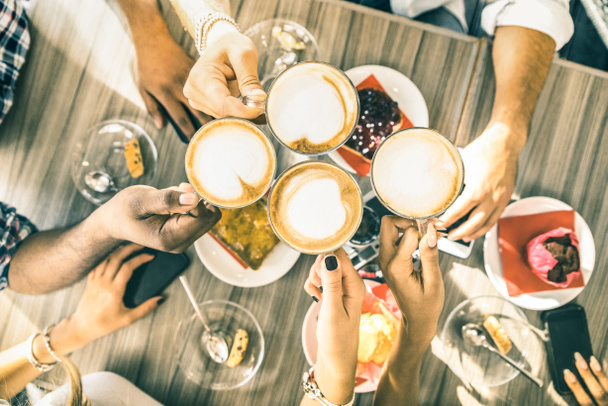 Friends group drinking cappuccino at coffee bar restaurant - People hands toasting at fashion cafeteria with upper view point - Winter drinks concept with men and women at cafe - Warm vintage filter - Photo, image
