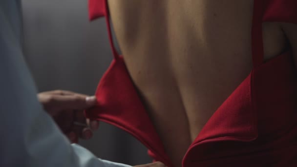 marido cariñoso ayuda a la esposa a ponerse un vestido rojo elegante, cierra la cremallera en la espalda
 - Metraje, vídeo