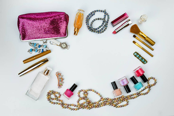 косметика, ювелирные изделия, парфюмерия и красивая розовая косметическая сумка на белом фоне, вид сверху
 - Фото, изображение