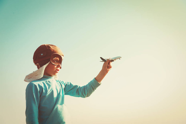 kask ve gözlük küçük çocuk oynamak oyuncak uçakla gökyüzünde - Fotoğraf, Görsel