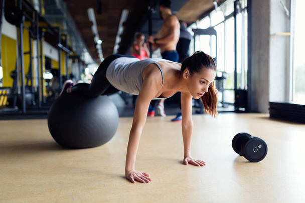 Young attractive woman exercising with swiss ball in gym - Foto, immagini