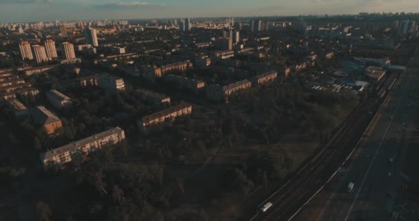 Aerial of streets and high-rise buildings at sunrise. Summer morning cityscape from a bird's eye view. Flight over the metropolis. Sunny morning, blue sky. A lot of green trees on the streets. - Felvétel, videó
