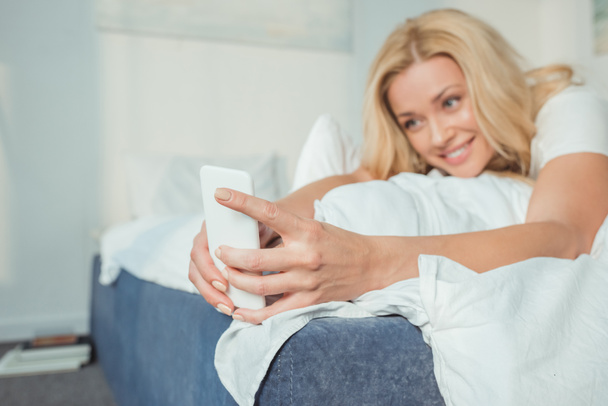 woman using smartphone in bed - Фото, изображение