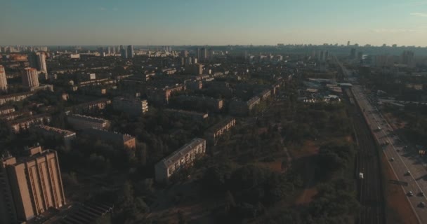 Aerial of streets and high-rise buildings at sunrise. Summer morning cityscape from a bird's eye view. Flight over the metropolis. Sunny morning, blue sky. A lot of green trees on the streets. - Filmati, video