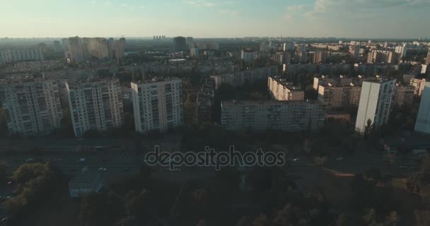 Aerial of streets and high-rise buildings at sunrise. Summer morning cityscape from a bird's eye view. Flight over the metropolis. Sunny morning, blue sky. A lot of green trees on the streets. - Footage, Video