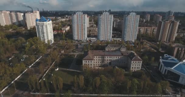 Aerial of streets and high-rise buildings at sunrise. Summer morning cityscape from a bird's eye view. Flight over the metropolis. Sunny morning, blue sky. A lot of green trees on the streets. - Materiał filmowy, wideo