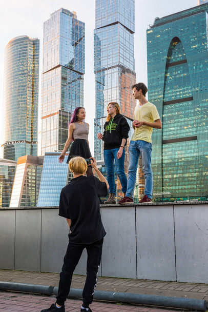 Moscow, Russia - November 2. 2017. Teenagers are photographed in background of skyscrapers of Moscow City - 写真・画像