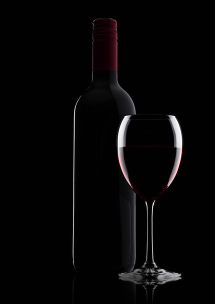 Glass of red wine with bottle with shape on black - Fotoğraf, Görsel