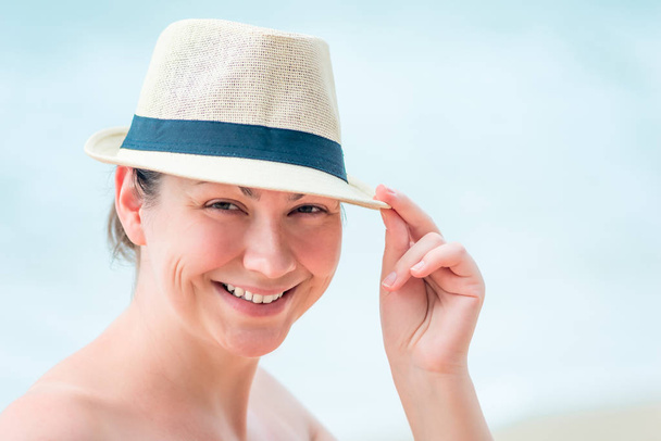 Porträt einer glücklichen Frau am Strand mit Strohhut - Foto, Bild