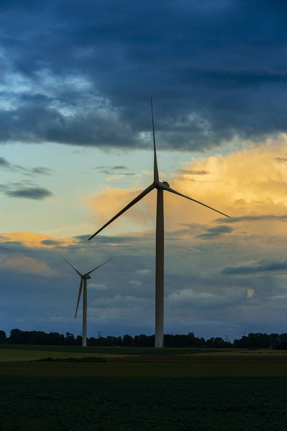 Větrná turbína pro výrobu elektrické energie v zemědělské oblasti na zamračený den v regionu Normandie, Francie. Obnovitelné zdroje energie, průmyslové zemědělství koncepce. Prostředí šetrné energetické produkce - Fotografie, Obrázek