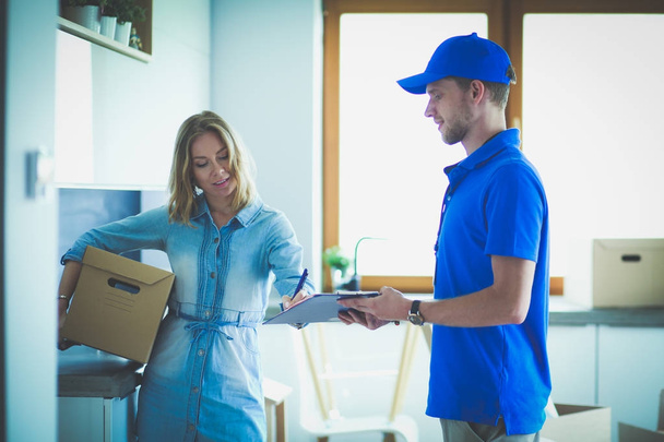Smiling delivery man in blue uniform delivering parcel box to recipient - courier service concept. Smiling delivery man in blue uniform - Foto, imagen