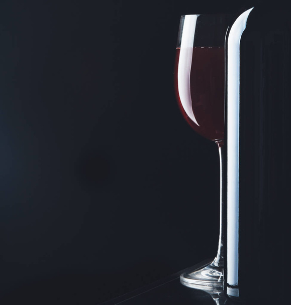 Glass of wine and a bottle on black background - Фото, зображення