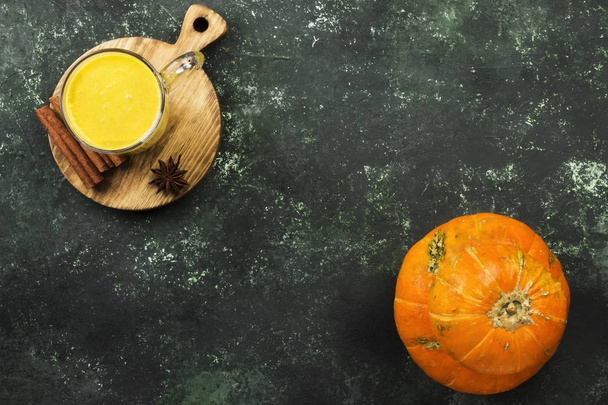 Pumpkin latte with spices (cinnamon, anise) on a green backgroun - 写真・画像