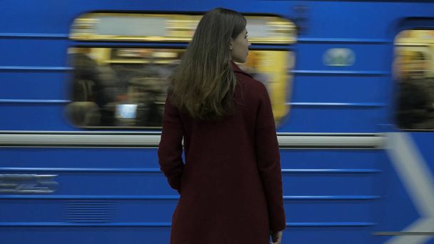 Mädchen wartet an der U-Bahn-Station auf einfahrenden Zug. Rückansicht eines Mädchens, das am Bahnhof wartet. Zug kommt an - Foto, Bild