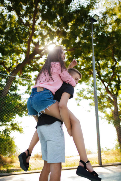Портрет молодого хлопчика тримає красиву дівчину на спині і розважається, проводячи час у парку разом
 - Фото, зображення
