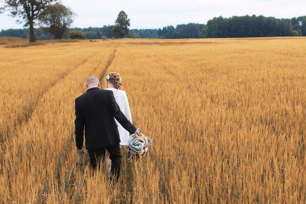 Net getrouwd liefhebbers wandelen in een veld in herfstdag - Foto, afbeelding