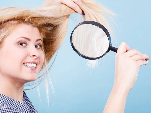 Woman looking at hair through magnifying glass - Foto, imagen