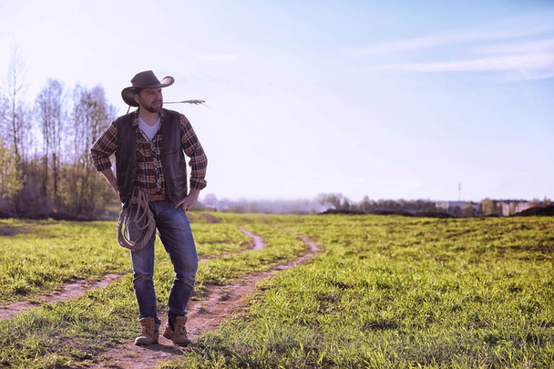 Cowboy standing in a field at sunset - Photo, Image