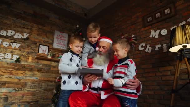 Dost kardeşler Noel Baba çizgi film tablet ile yemyeşil ağaç Noel için dekore edilmiş oda dahil etmek sormak - Video, Çekim