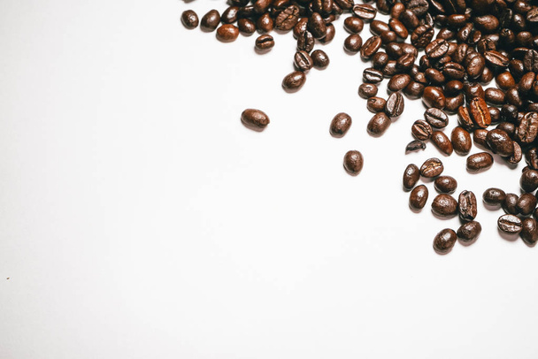 on the white surface lie dark brown grains of fragrant coffee - Φωτογραφία, εικόνα